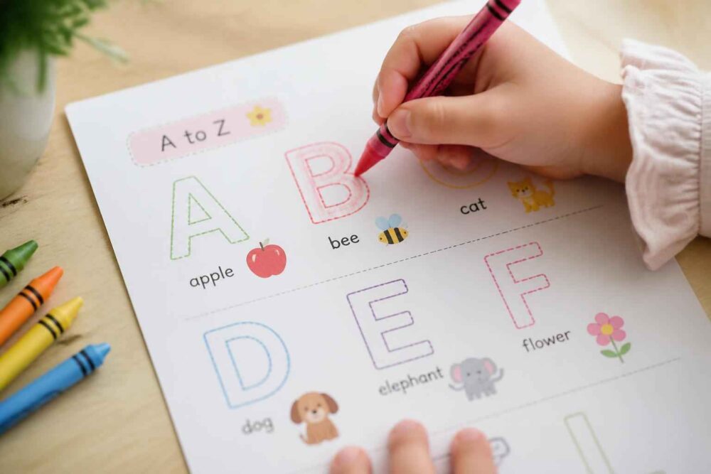 Dziecko koloruje angielskie litery z obrazkami zwierząt, owoców i kwiatów